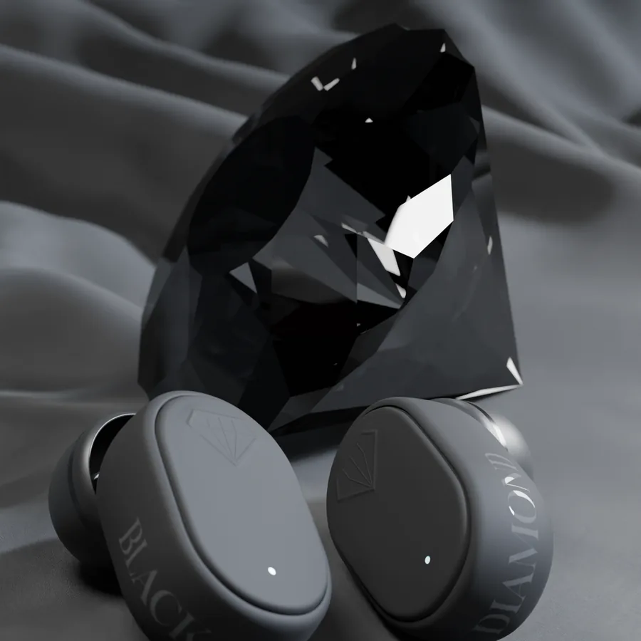 Wireless earbuds beside a faceted black stone, on grey fabric